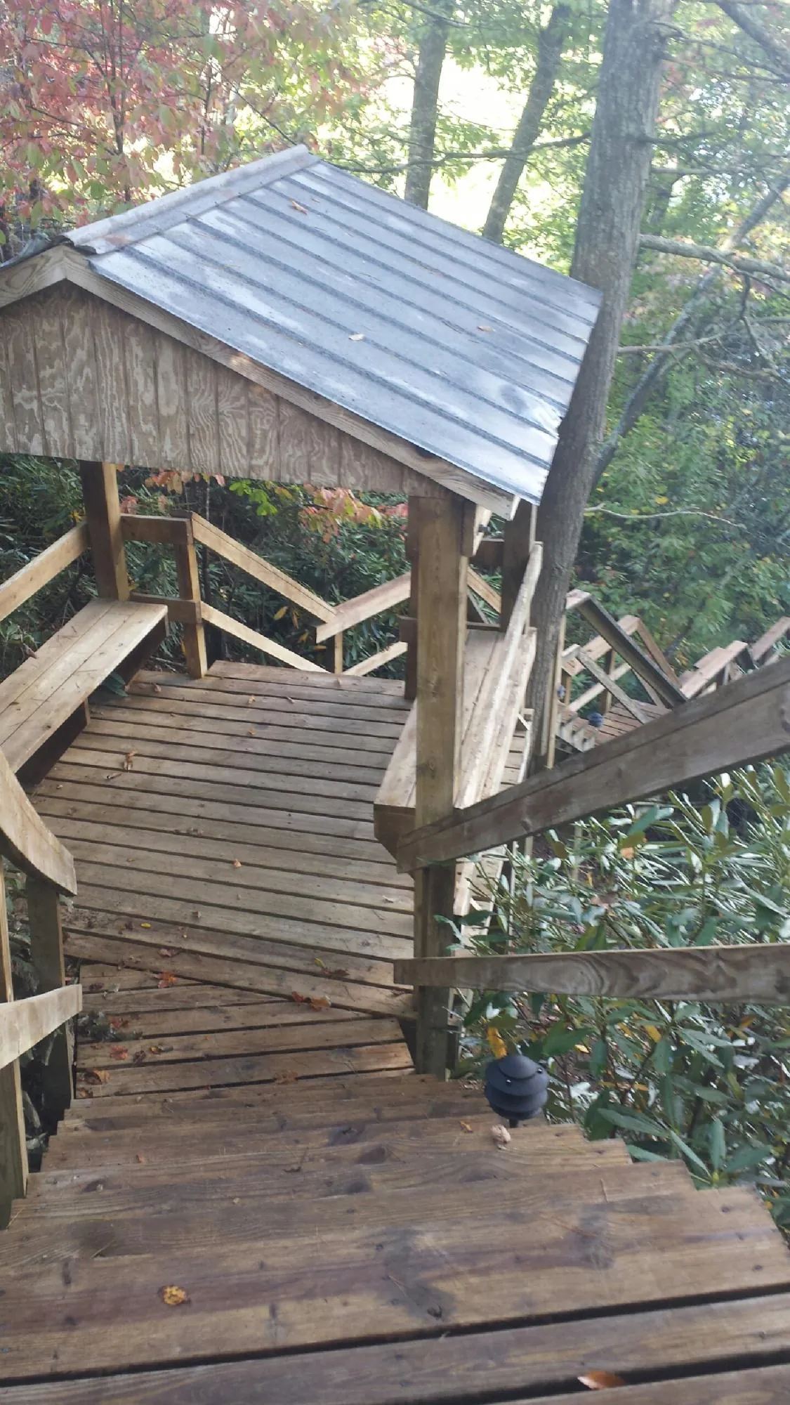 Metal roofed shelter over wooden steps on a wooded walkway — Skylight Repair & Installation work by our crew in Gattman