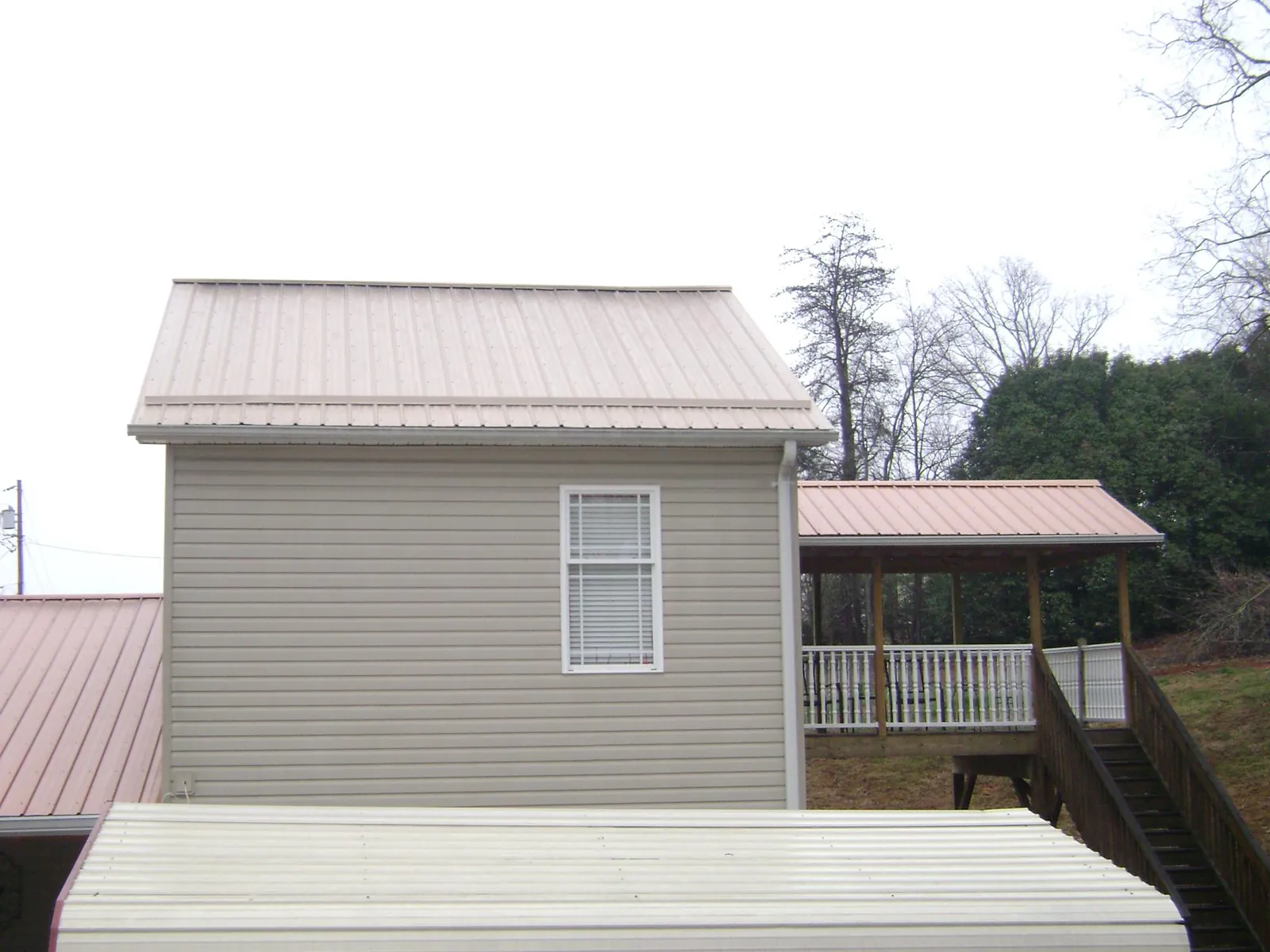 Tan metal roofs on a two story addition and attached porch, from a Roof Replacement job in Gattman