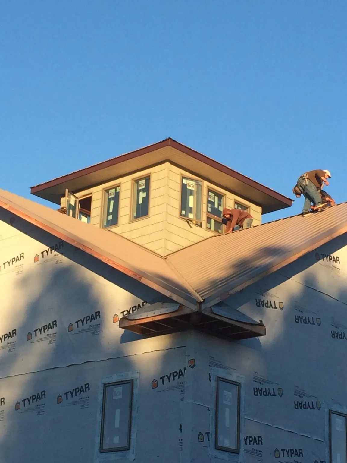 Roofers working around a rooftop cupola on a new metal roof at sunset — Roof Waterproofing in Gattman by Roofing Brothers